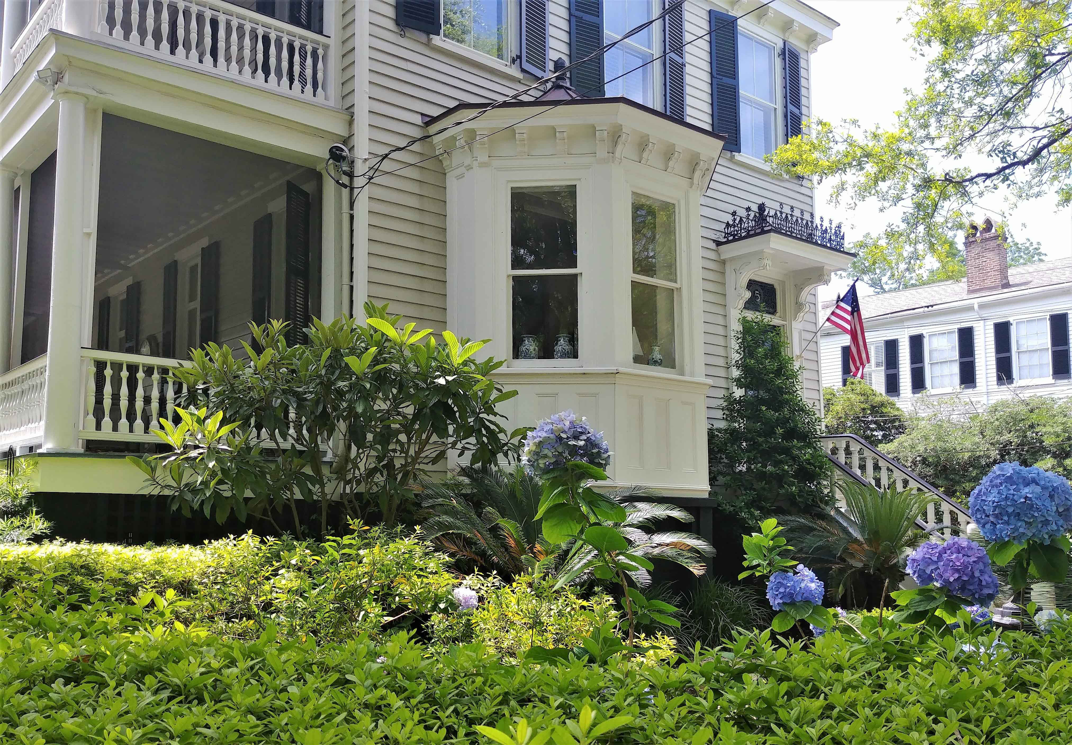 Colonial house with green shrubs and the American flag