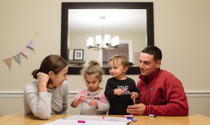 Young family coloring at the family table.
