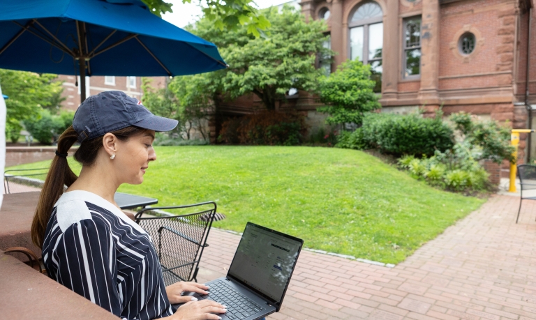 Woman checking her WSB bank account on her computer outside the library.