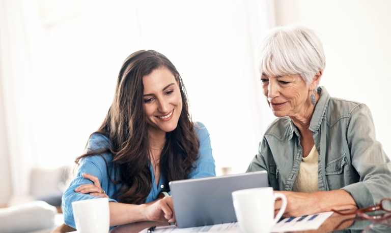 Young woman helping an older woman on the laptop.