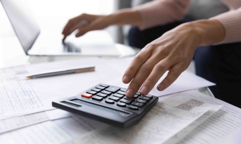 A person's hands resting on a calculator and papers.