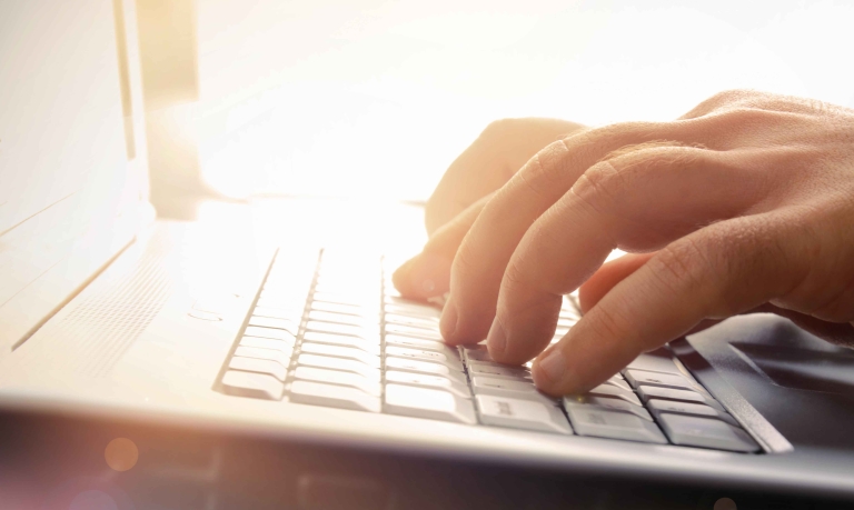 Fingers typing on a laptop keyboard.