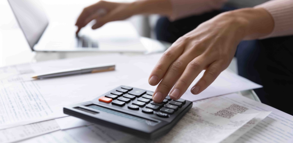 A person's hands resting on a calculator and papers.