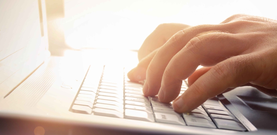 Fingers typing on a laptop keyboard.