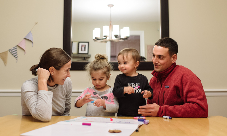 A young family sitting at a table doing crafts.