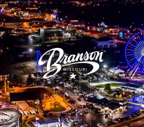 Nighttime with a blue-lit ferris wheel with the name Branson on it.
