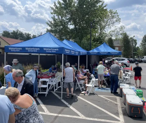 A gathering of customers at a branch parking lot with blue branded tents.