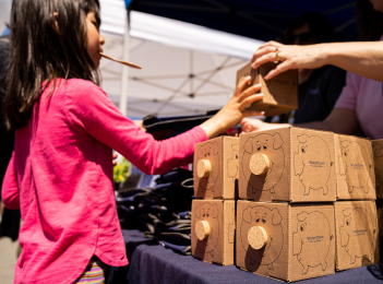 WSB employee offering a piggy bank to a girl at a Town Day.