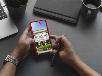 Person access the WSB Mobile Banking app on their phone with a laptop nearby.