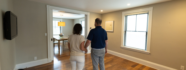 A couple walking through an empty room of their newly built house.
