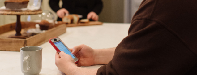 Man sitting at the kitchen counter review his WSB Mobile Business app.