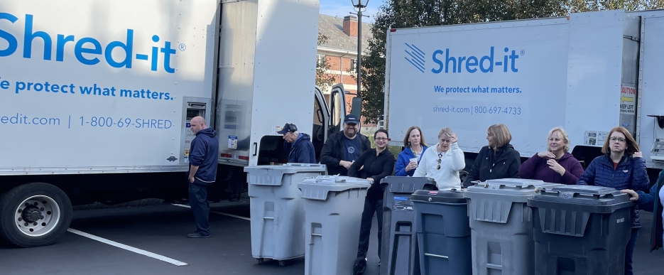 A group of WSB employee volunteers standing in front of Shred-It trucks during a Shred Day event.
