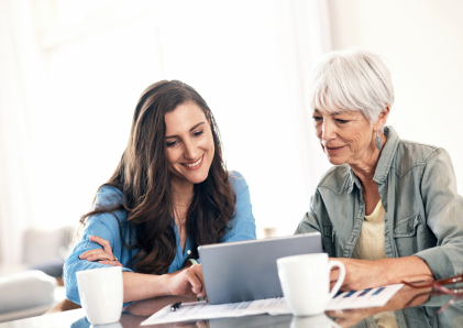 Young woman helping an older woman on the laptop.