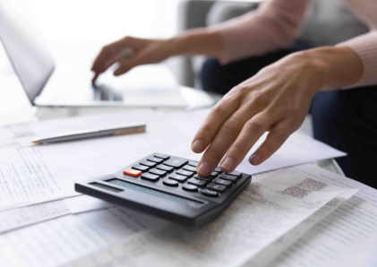 A person's hands resting on a calculator and documents.