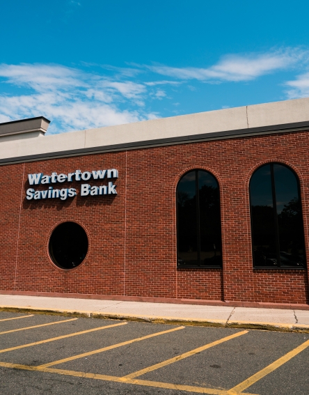 Brick building with the Watertown Savings Bank name and entrance to the drugstore.