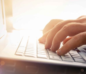 Fingers typing on a laptop keyboard.