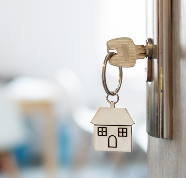 Key with a home keychain inside an opened door.