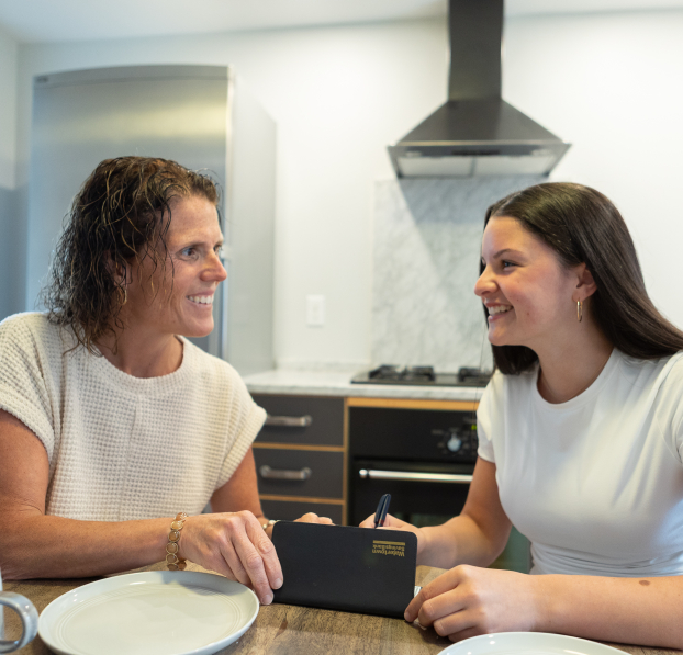 Mom and daughter doing their banking at their kitchen table.